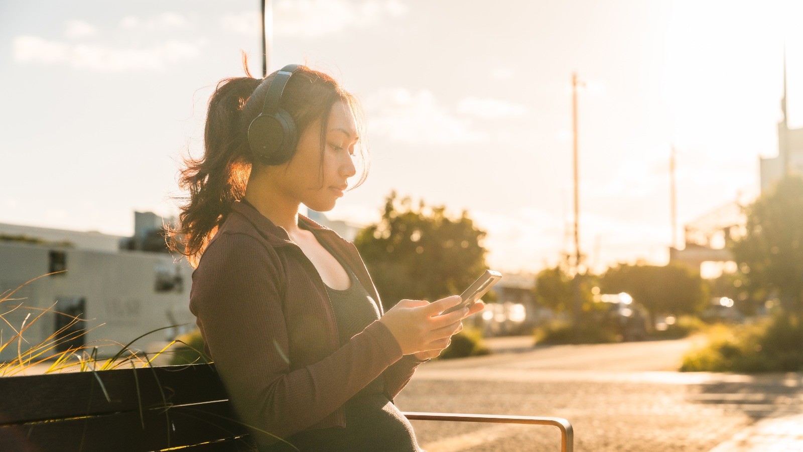 Woman on her phone with headphones on. 