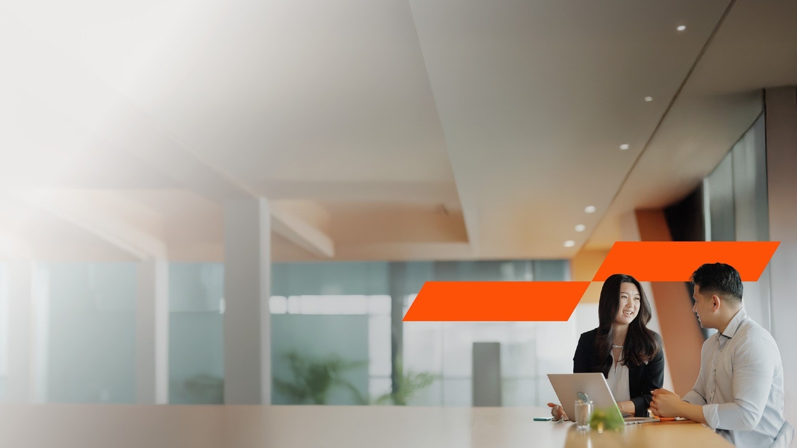 Two colleagues discussing with a laptop in front of then in a spacious lobby.