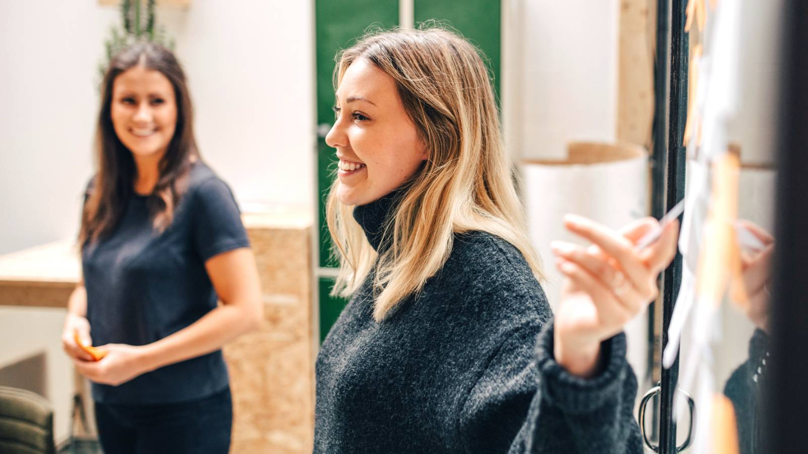Professional woman smiling while pointing at board