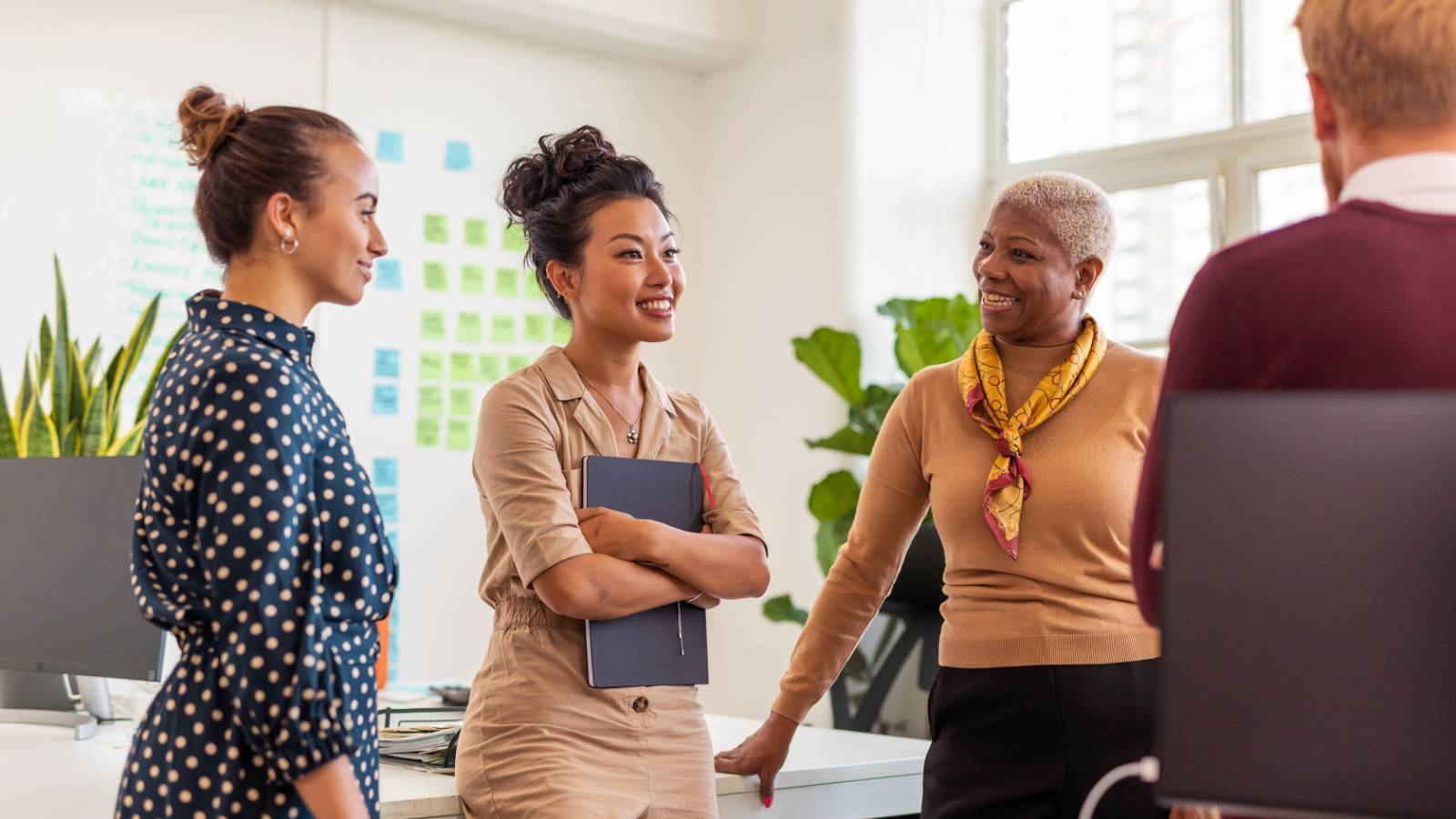 Young female holding a binder and talking to colleagues or mentors