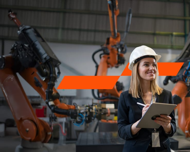 A woman working in an industrial setting, holding an iPad and a stylus in her hands.