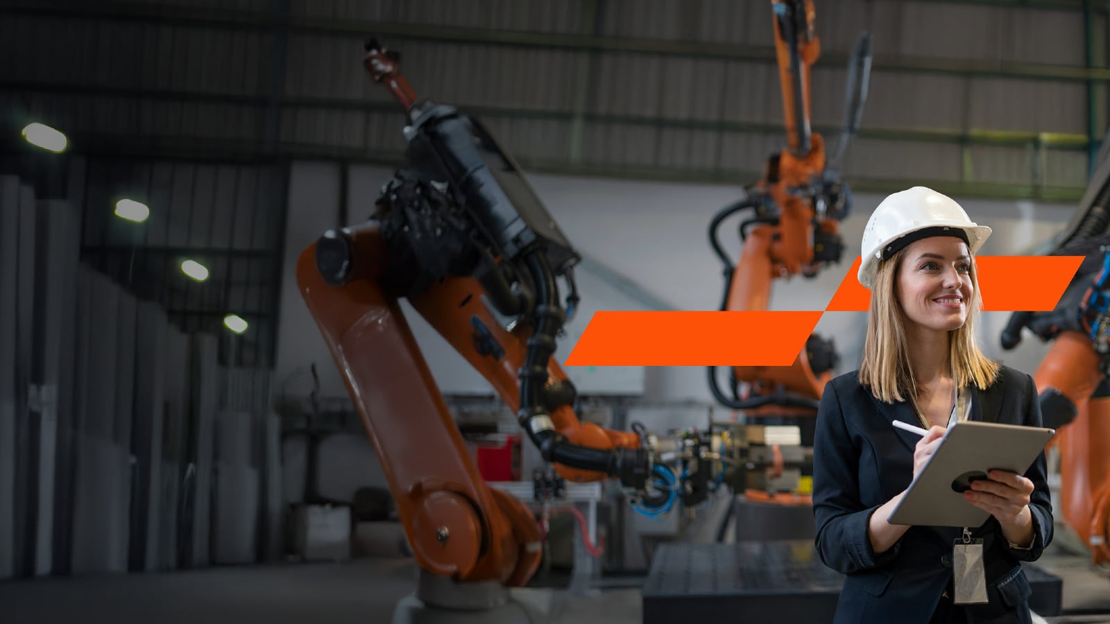 A woman working in an industrial setting, holding an iPad and a stylus in her hands.