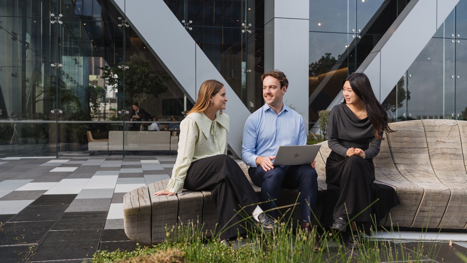 Group of interns talking on a bench in a contemporary office.